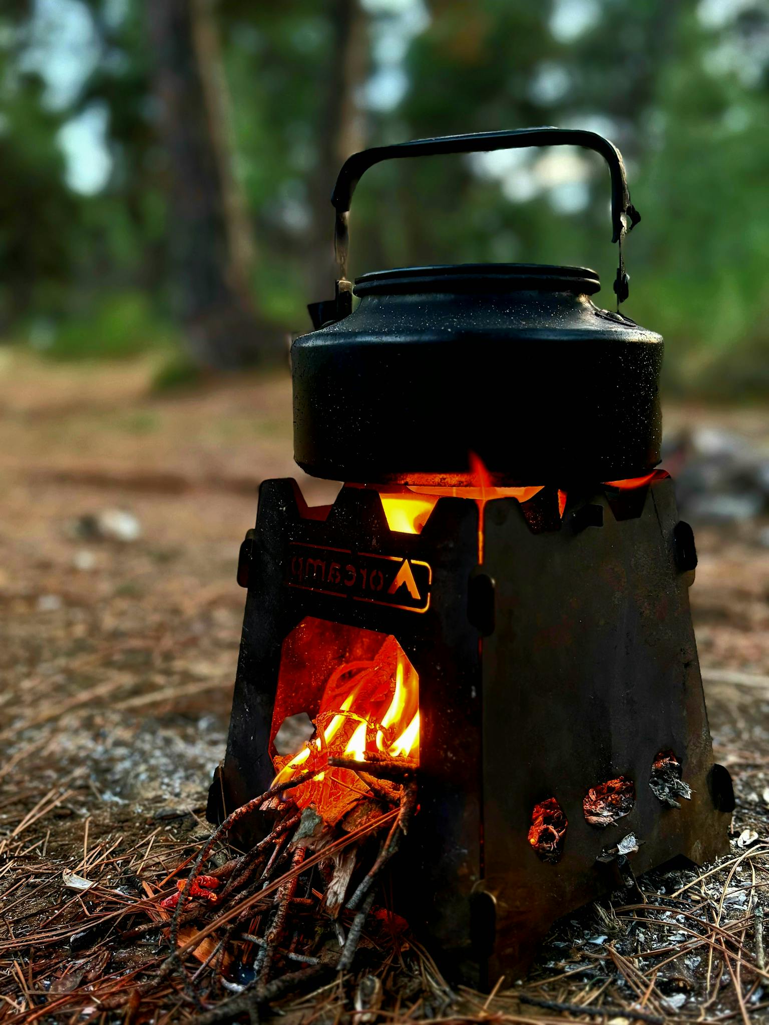 A rustic black tea kettle boiling on a campfire stove in a forest setting in Tekirdağ, Türkiye.