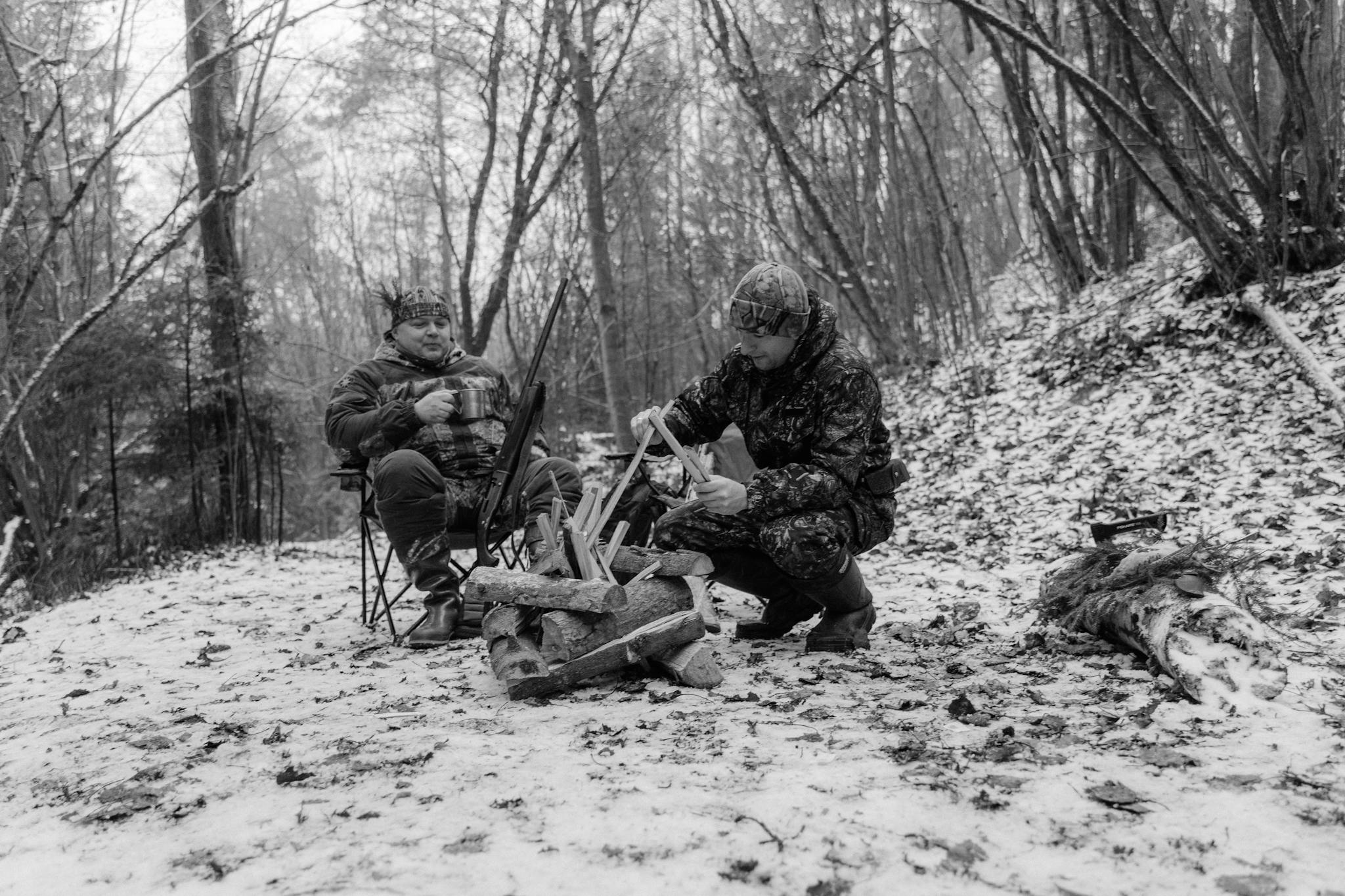 Two men enjoy a cozy winter camping experience in a snowy forest.