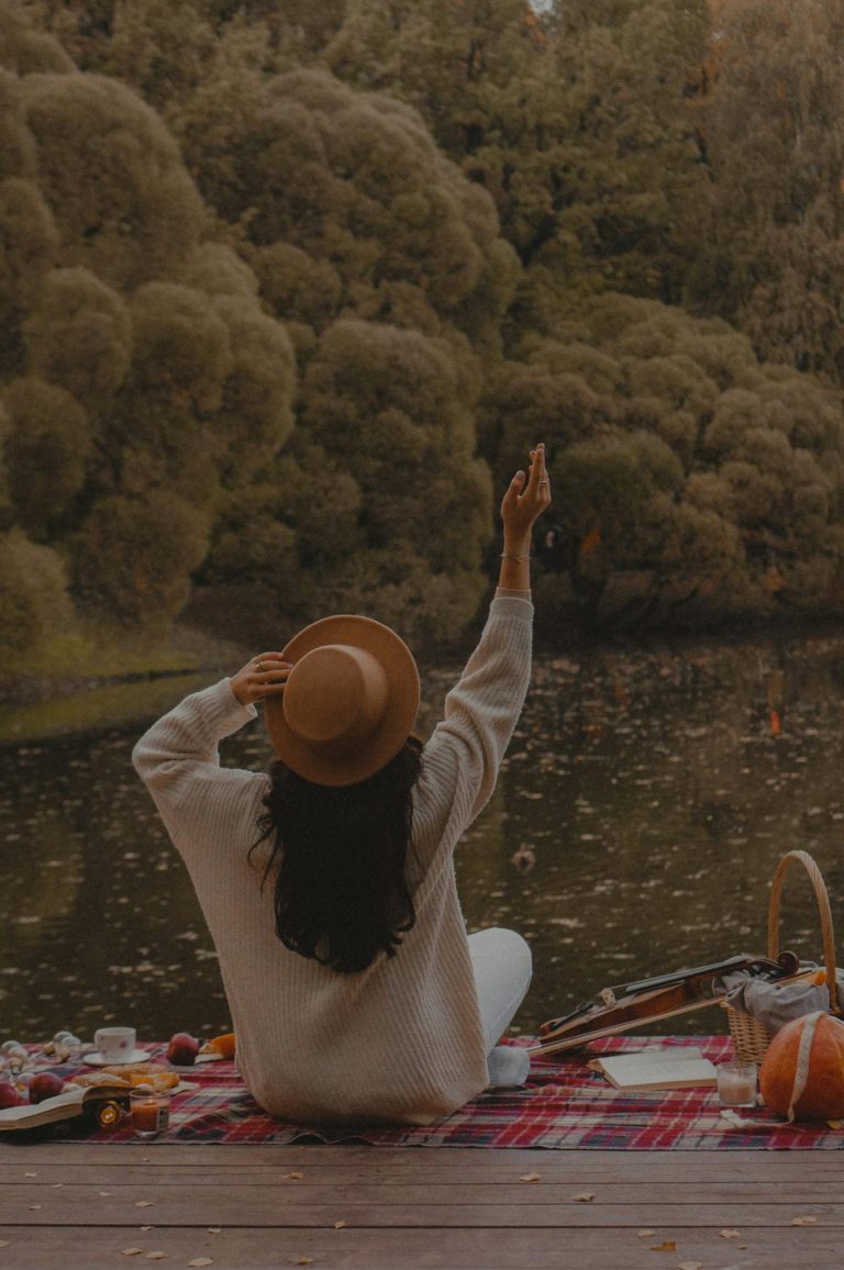 Woman enjoying a serene picnic by a tranquil autumn lake.