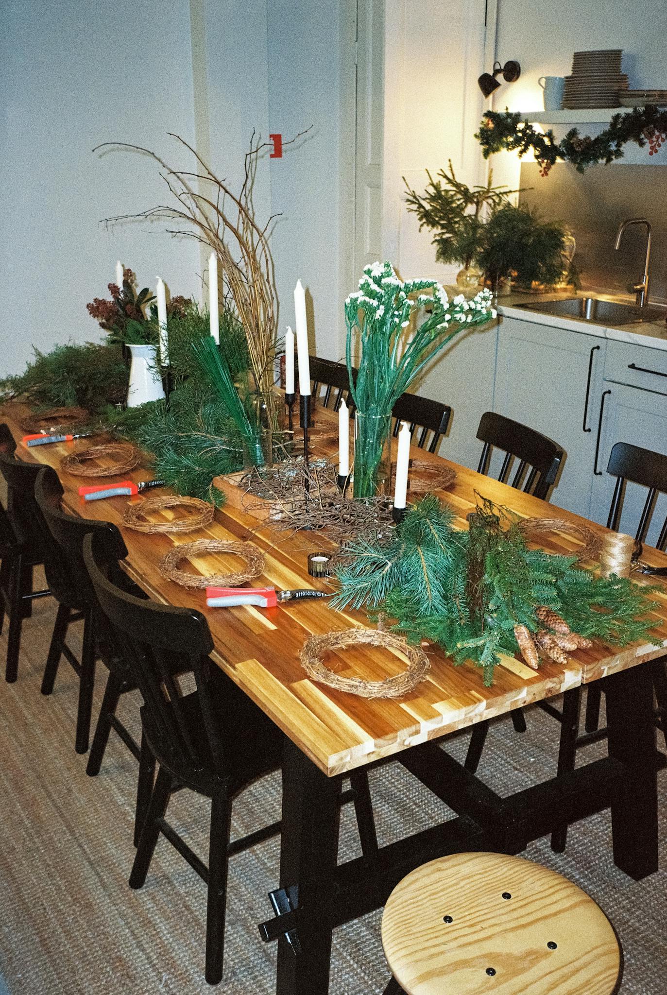Wooden table with festive Christmas decorations and natural greenery indoors.